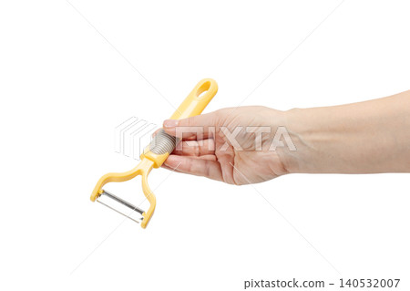 Woman's hand holding a vegetable peeler on the white background. Woman's hand holding a vegetable peeler on the white background. 140532007