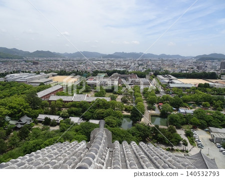 A view of the shachi (mythical fish-like creature) roof tiles and the city of Himeji as seen through the lattice windows of the main keep of Himeji Castle. A view of the shachi (mythical fish-like creature) roof tiles and the city of Himeji as seen through the lattice windows of the main keep of Himeji Castle. 140532793
