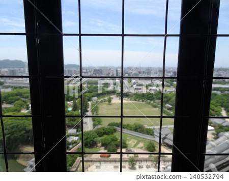 A view of the shachi (mythical fish-like creature) roof tiles and the city of Himeji as seen through the lattice windows of the main keep of Himeji Castle. A view of the shachi (mythical fish-like creature) roof tiles and the city of Himeji as seen through the lattice windows of the main keep of Himeji Castle. 140532794