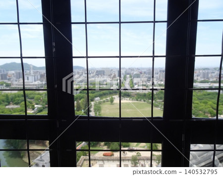A view of the shachi (mythical fish-like creature) roof tiles and the city of Himeji as seen through the lattice windows of the main keep of Himeji Castle. A view of the shachi (mythical fish-like creature) roof tiles and the city of Himeji as seen through the lattice windows of the main keep of Himeji Castle. 140532795