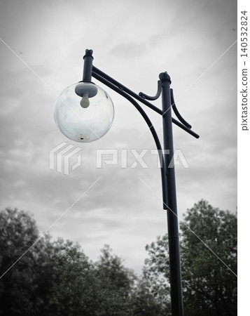 Vintage street lamp post with round glass globe against cloudy sky 140532824