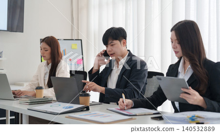 Asian business team collaborating on laptops in modern office Asian business team collaborating on laptops in modern office 140532889