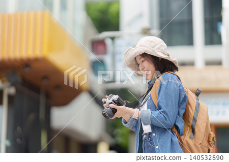 Asian woman tourist reviewing photos on camera in city Asian woman tourist reviewing photos on camera in city 140532890