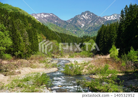 A spring landscape of fresh greenery and a clear stream against the backdrop of a blue sky and the snow-capped Mt. Daigenta. Ver1 A spring landscape of fresh greenery and a clear stream against the backdrop of a blue sky and the snow-capped Mt. Daigenta. Ver1 140532952