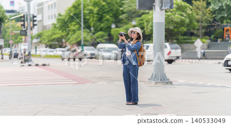 Asian woman tourist taking photo with camera on urban street Asian woman tourist taking photo with camera on urban street 140533049