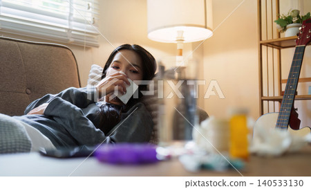 Asian woman resting on couch feeling sick with medicine in foreground 140533130