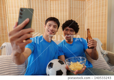Asian and Southeast Asian men taking selfie while watching football Asian and Southeast Asian men taking selfie while watching football 140533243