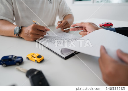 Two men signing car purchase agreement document at office desk 140533285