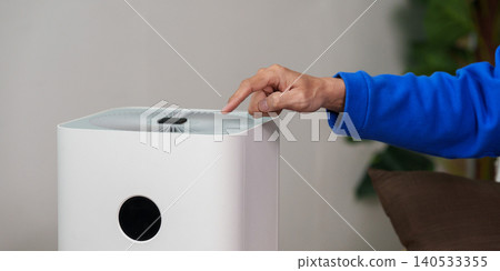Hand pressing button on modern air purifier for clean air and home health Hand pressing button on modern air purifier for clean air and home health 140533355