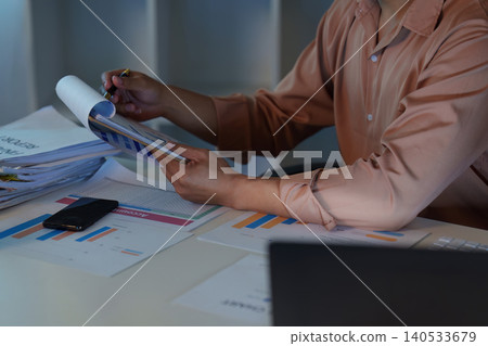 Asian man reviewing finance report and data analysis at remote home office Asian man reviewing finance report and data analysis at remote home office 140533679