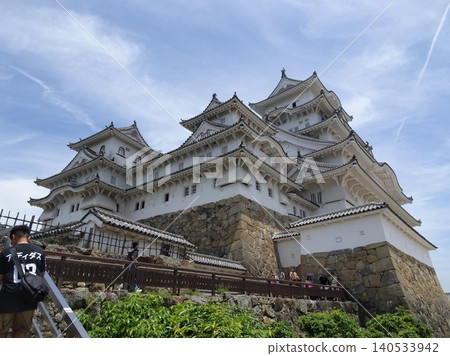 The majestic figures of Himeji Castle's main keep and eastern smaller keep, towering against the blue sky as seen from Bizenmaru. 140533942