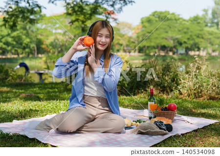 Asian woman listening to music with headphones in outdoor park for wellness Asian woman listening to music with headphones in outdoor park for wellness 140534098