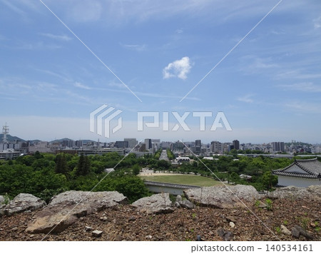 A view of the cityscape from beyond the stone walls of Himeji Castle, overlooking the San-no-maru Square and Otemae Street stretching straight towards Himeji Station. 140534161