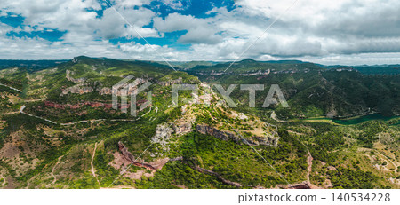 Aerial panoramic view of Siurana village perched on dramatic cliffs surrounded by rugged mountains, deep valleys and forested landscapes Aerial panoramic view of Siurana village perched on dramatic cliffs surrounded by rugged mountains, deep valleys and forested landscapes 140534228