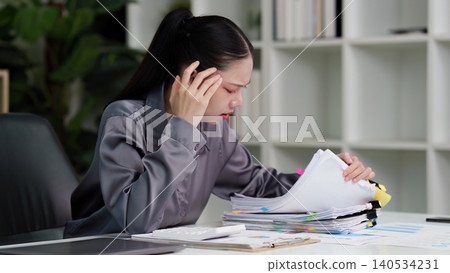 Stressed Asian businesswoman overwhelmed by paperwork in office Stressed Asian businesswoman overwhelmed by paperwork in office 140534231