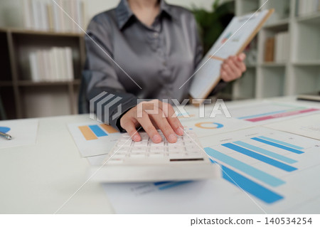 Asian woman professional doing finance analysis with calculator and charts in office Asian woman professional doing finance analysis with calculator and charts in office 140534254