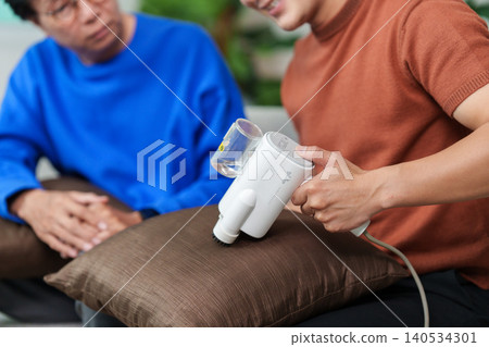 Asian man cleaning home cushion with appliance, senior observing, household chore Asian man cleaning home cushion with appliance, senior observing, household chore 140534301