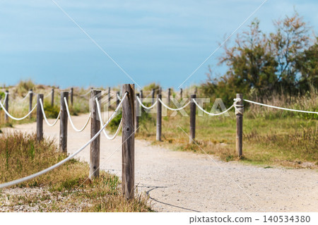 Rope lined walking trail crossing protected coastal dunes toward Mediterranean shoreline in Les Madrigueres nature reserve near Sant Salvador Rope lined walking trail crossing protected coastal dunes toward Mediterranean shoreline in Les Madrigueres nature reserve near Sant Salvador 140534380