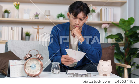 Asian man in his 20s or 30s planning personal finance and budget at home Asian man in his 20s or 30s planning personal finance and budget at home 140534493