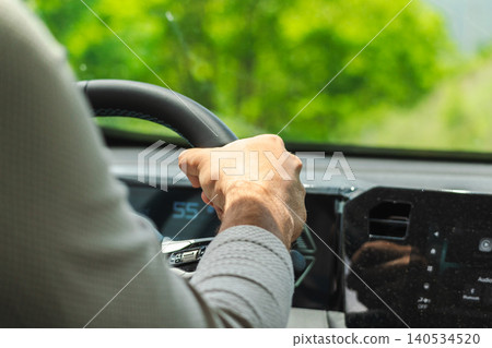 Driver hand on steering wheel during scenic road trip through countryside Driver hand on steering wheel during scenic road trip through countryside 140534520