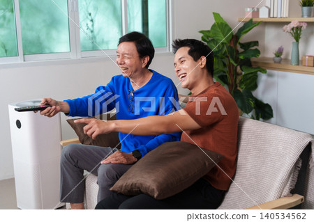 Happy Asian senior man and younger man watching television at home Happy Asian senior man and younger man watching television at home 140534562