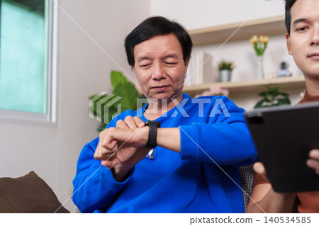 Asian senior man checking smartwatch for health monitoring with younger man 140534585