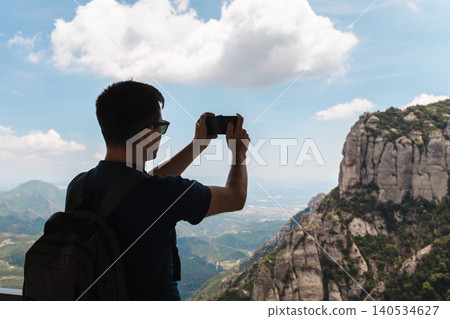 Traveler capturing mountain scenery with smartphone at Montserrat viewpoint in Spain Traveler capturing mountain scenery with smartphone at Montserrat viewpoint in Spain 140534627