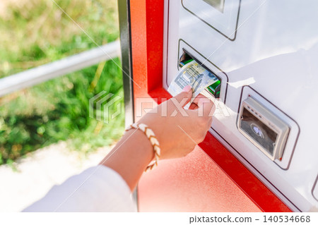 Woman inserting euro banknote into automated parking payment machine, paying parking fee at self service terminal Woman inserting euro banknote into automated parking payment machine, paying parking fee at self service terminal 140534668