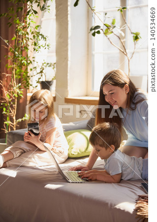 Children using smartphone and laptop while mother interacts with them at home Children using smartphone and laptop while mother interacts with them at home 140534669