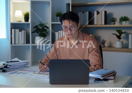 Asian man in 20s working late at night in home office 140534850