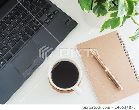 白色桌上放著咖啡、筆記型電腦和觀賞植物。 白色桌上放著咖啡、筆記型電腦和觀賞植物。 140534873