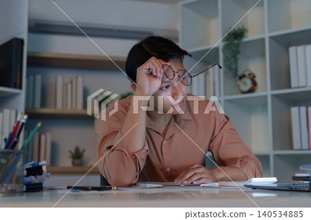 Thoughtful Asian man in 20s working late in home office Thoughtful Asian man in 20s working late in home office 140534885