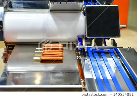 Modern industrial food production machinery manufacturing fresh sausages with wooden sticks in factory Modern industrial food production machinery manufacturing fresh sausages with wooden sticks in factory 140534891