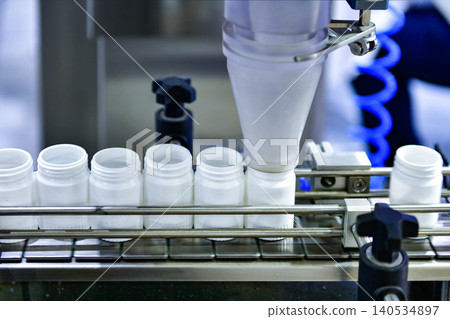 Automatic white plastic bottle filling machine working on conveyor belt line in pharmaceutical factory Automatic white plastic bottle filling machine working on conveyor belt line in pharmaceutical factory 140534897