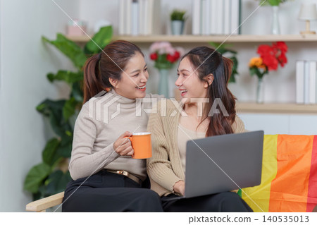 Asian LGBTQ couple working on laptop at home with rainbow flag, remote work. 140535013