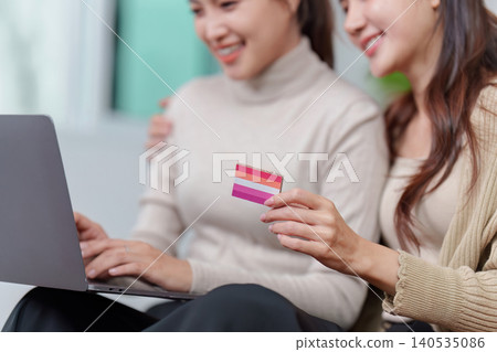 Asian LGBTQ women online shopping with laptop and pride credit card Asian LGBTQ women online shopping with laptop and pride credit card 140535086