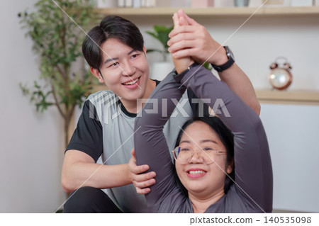 Asian man training woman stretching at home, wellness fitness Asian man training woman stretching at home, wellness fitness 140535098