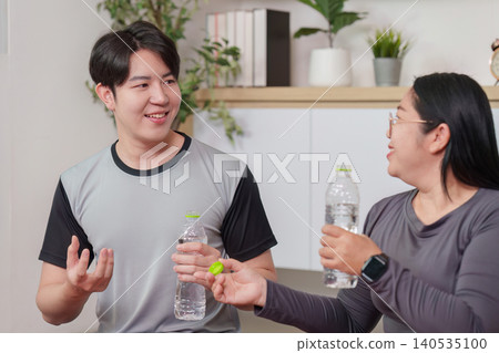 Asian woman and man drinking water and talking, hydration wellness Asian woman and man drinking water and talking, hydration wellness 140535100