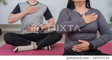 Asian couple doing mindfulness breathing meditation during home workout Asian couple doing mindfulness breathing meditation during home workout 140535119