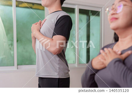 Asian man doing mindfulness breathing exercise during home workout Asian man doing mindfulness breathing exercise during home workout 140535120