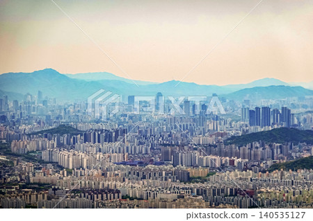 Dense apartment complex cityscape under a warm sunset sky with misty mountains in Seoul Dense apartment complex cityscape under a warm sunset sky with misty mountains in Seoul 140535127