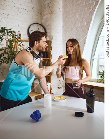 Sporty couple preparing healthy drink with lemon and protein at home kitchen. Sporty couple preparing healthy drink with lemon and protein at home kitchen. 140535363