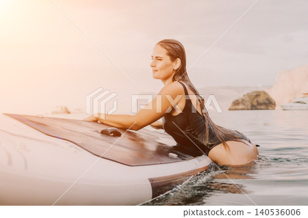 Woman Paddleboarding Ocean Sunset Enjoying Calm Water Activity at Golden Hour 140536006