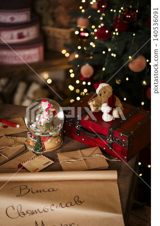 Christmas snow globe with Santa and small teddy bear in red hat on glowing xmas tree background 140536091