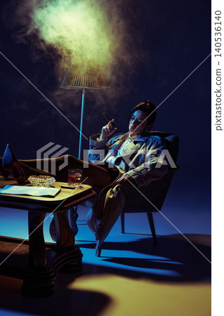 Woman smoking cigar and relaxing with whiskey in armchair under colored studio lighting. Woman smoking cigar and relaxing with whiskey in armchair under colored studio lighting. 140536140