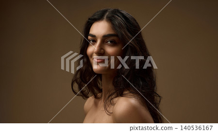 Brunette woman smiling with natural wavy hair on warm brown beauty background. Brunette woman smiling with natural wavy hair on warm brown beauty background. 140536167