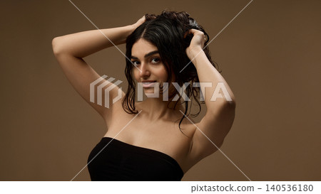 Beauty model with soft loose hair and glowing skin posing on warm brown background. Beauty model with soft loose hair and glowing skin posing on warm brown background. 140536180