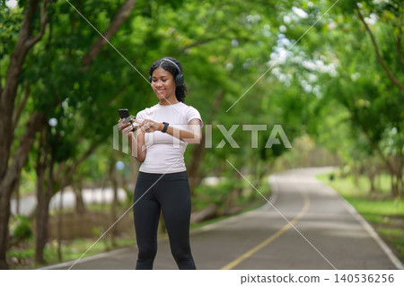 Black woman checking smartphone while exercising on park path for active lifestyle Black woman checking smartphone while exercising on park path for active lifestyle 140536256