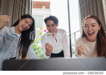 Excited Asian business team celebrating success at laptop in office Excited Asian business team celebrating success at laptop in office 140536305