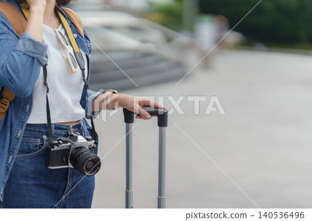 Cropped view of Asian woman traveler with luggage and camera for summer vacation journey outdoors Cropped view of Asian woman traveler with luggage and camera for summer vacation journey outdoors 140536496